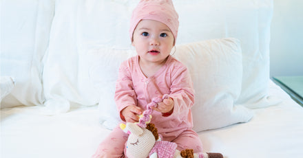 Baby in pink jumper with plush toy